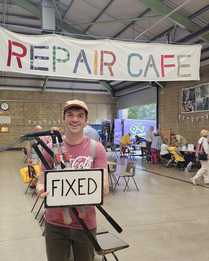 Volunteer holding a FIXED sign next to his repaired bagpipes