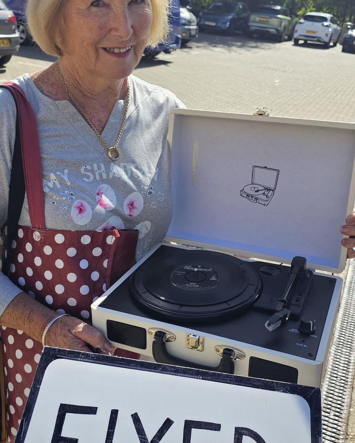 Visitor with her repaired record player and a FIXED sign