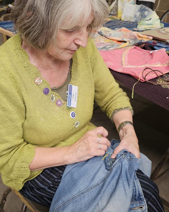Repair Cafe volunteer hand-sewing a pair of jeans